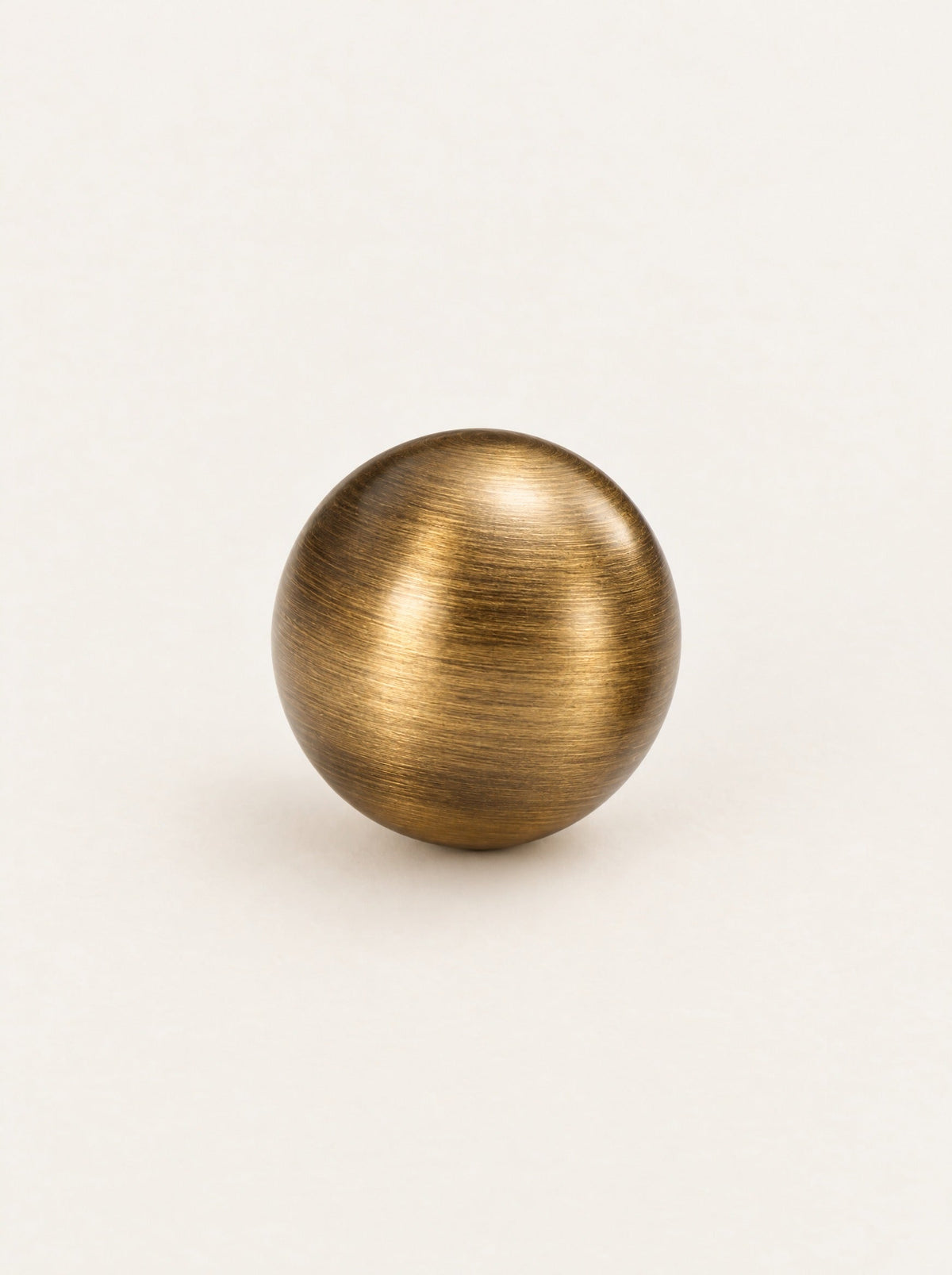 Bruno knob in aged brass, studio photo on a warm white background