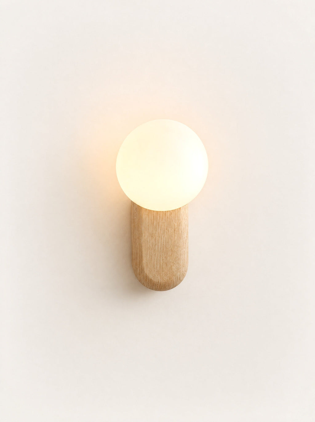 Buoy Wood & Opal Sconce switched on, studio photo on a warm white background