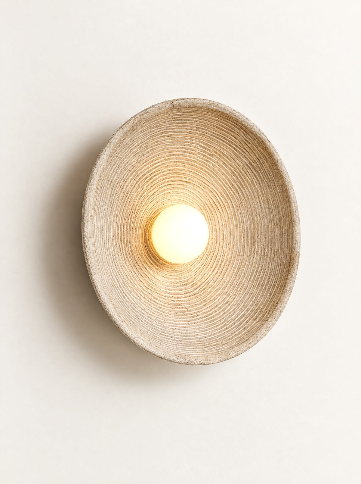 Ripple Disc Wall Light switched on, studio photo on a warm white background