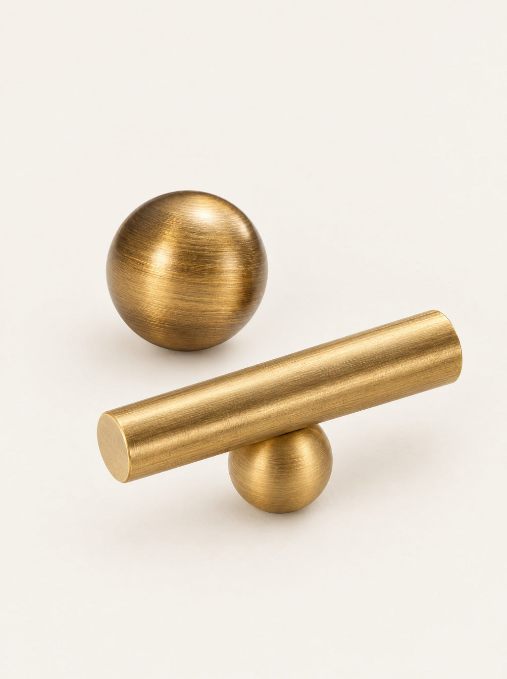 Sphere Brass Knob & Bar Pull, studio photo on a warm white background